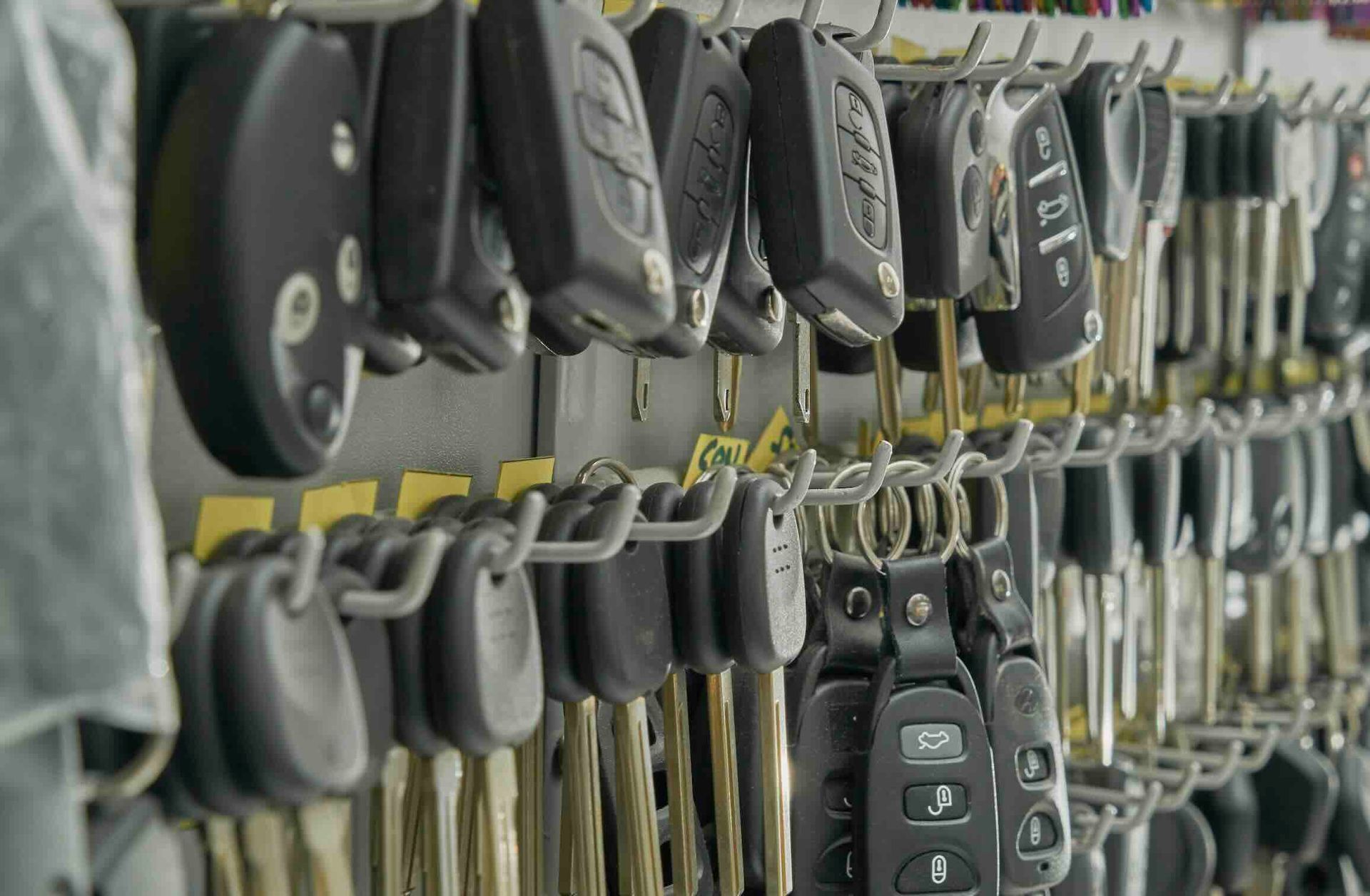A close-up view of numerous car key fobs and keys hanging in orderly rows on a wall-mounted rack.