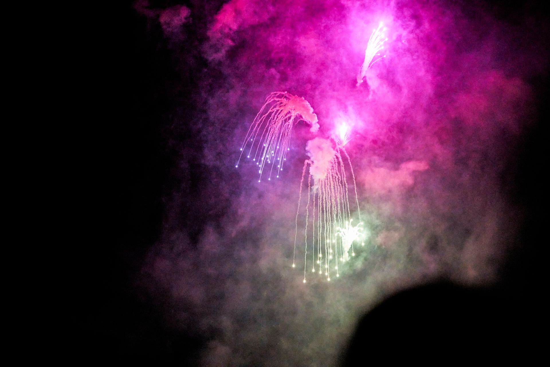 A person is watching a fireworks display in the night sky.