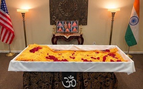 Alternative cardboard casket draped in a saffron cloth with flower petals