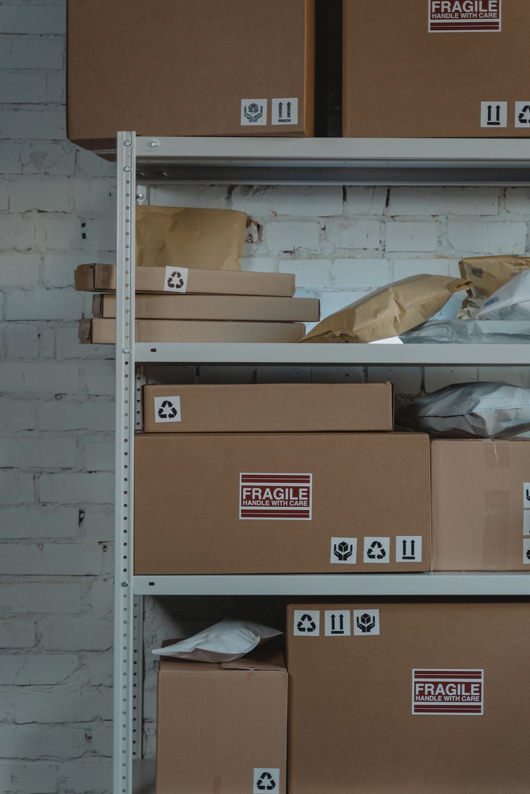 Metal storage shelves with cardboard boxes and packing materials in a warehouse-like room.