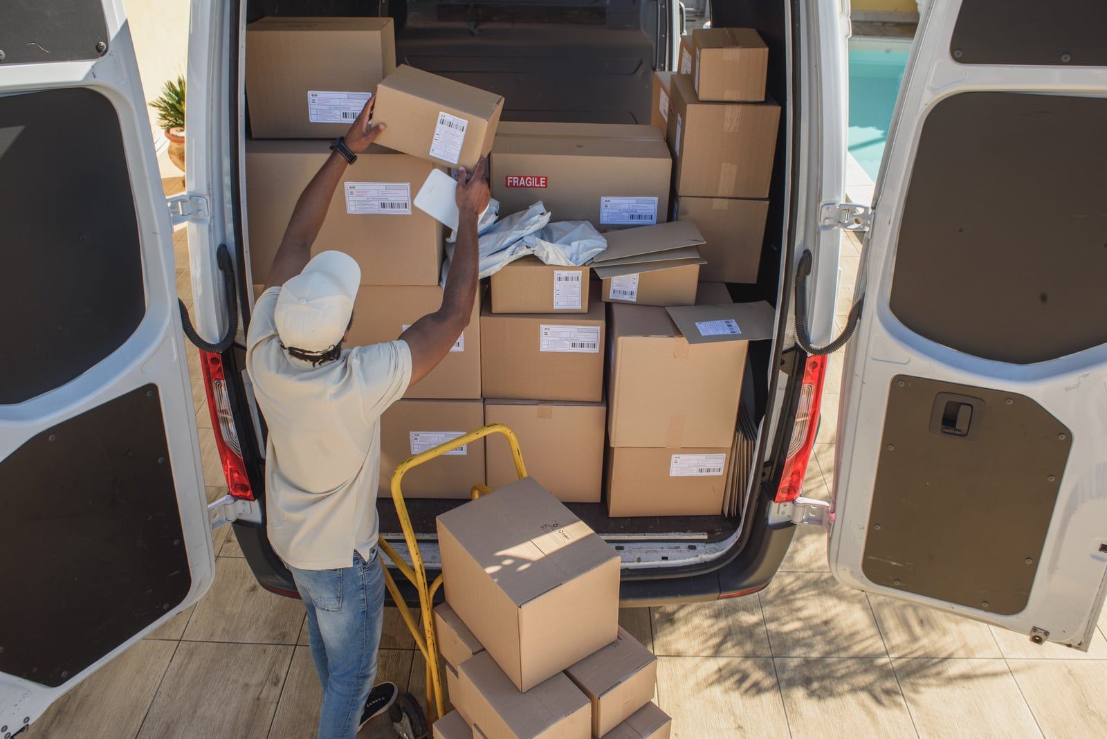 Person loading cardboard boxes into the back of a cargo van