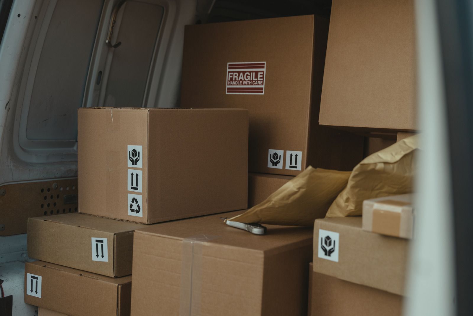 Cardboard boxes stacked inside a delivery van, with shipping labels visible.
