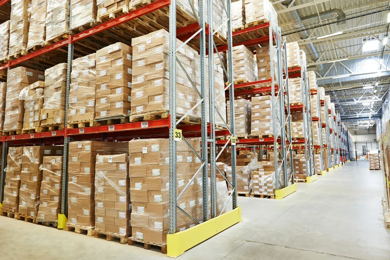 Warehouse aisles with tall pallet racks stacked with cardboard boxes
