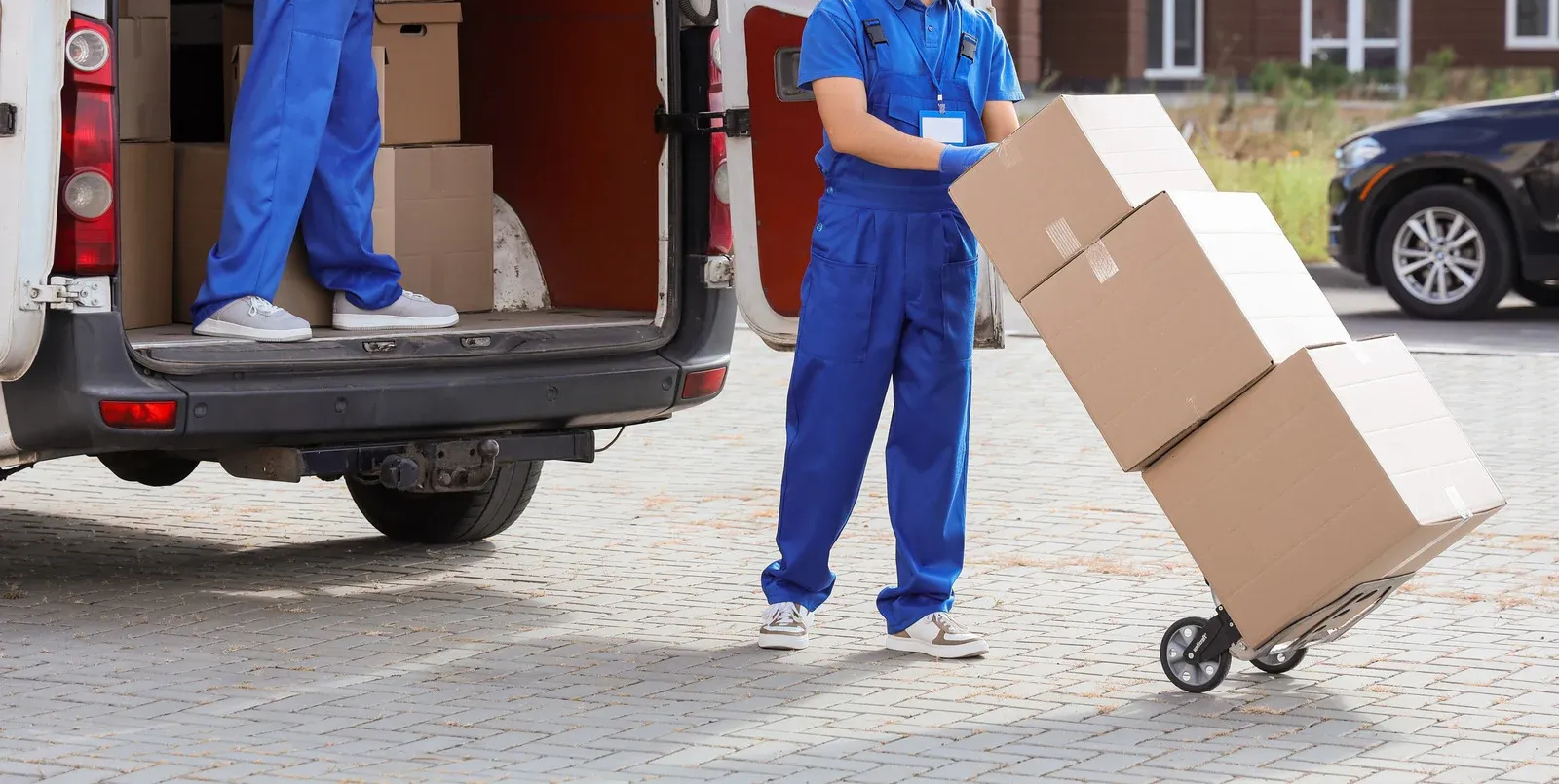 Delivery worker unloading cardboard boxes from a truck onto a hand truck outdoors