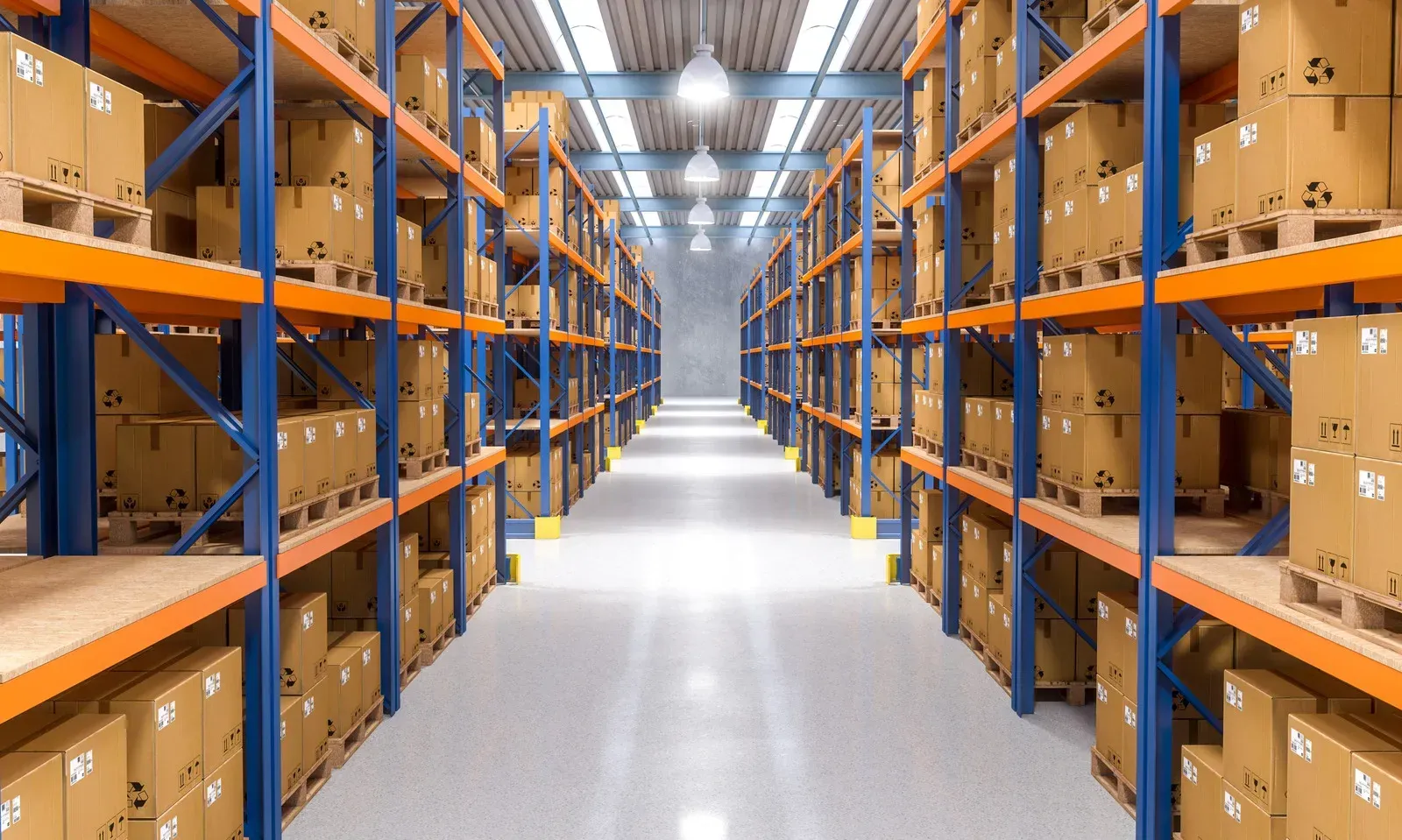 Long warehouse aisle with blue-and-orange shelving and stacked cardboard boxes