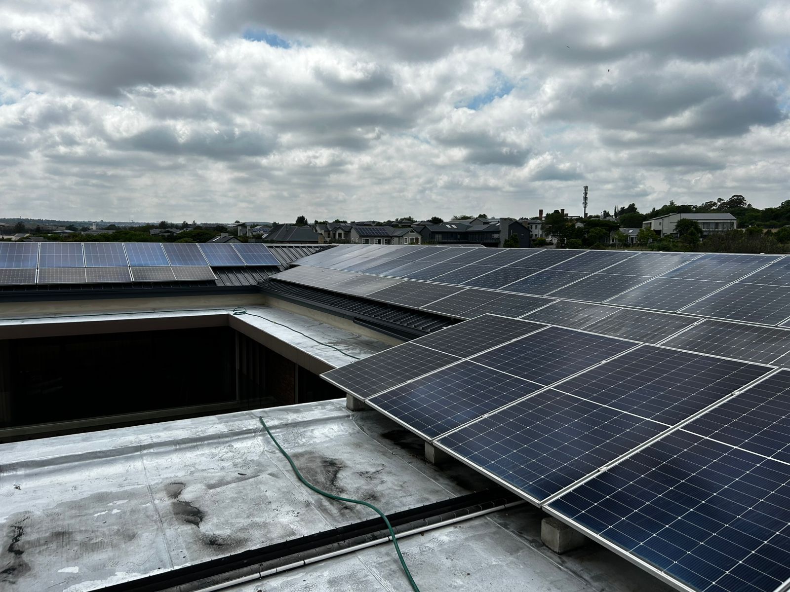 Solar panels mounted on a flat rooftop against a cloudy sky.