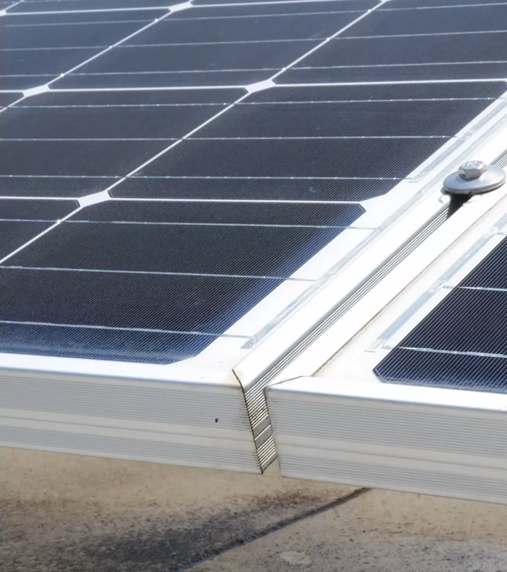 Close-up of two adjacent solar panels mounted on a frame with a metal clamp securing them together.