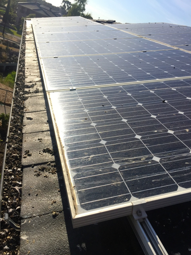 A close-up view of rooftop solar panels alongside a gravel-filled drainage area on a residential roof.