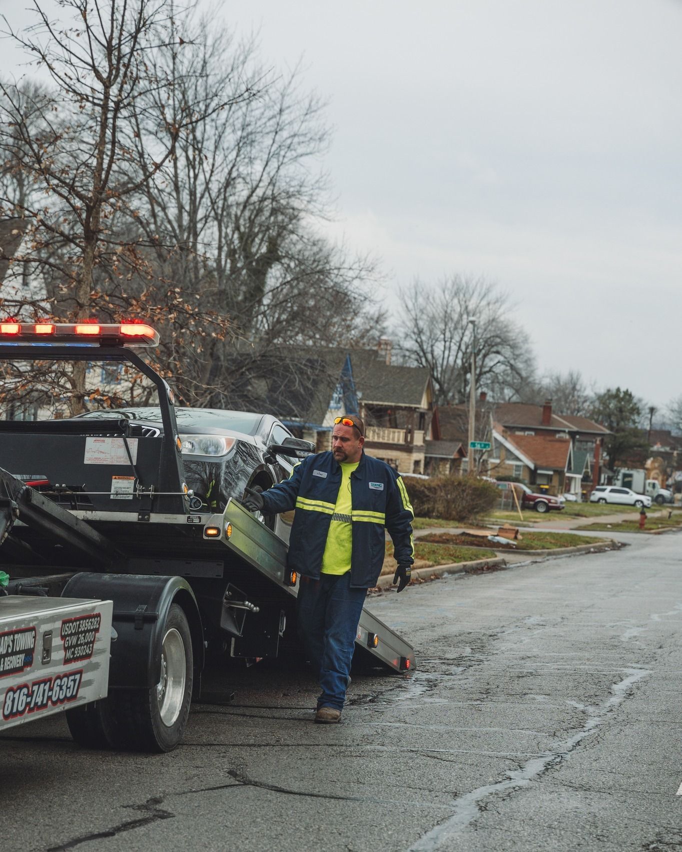 A man is standing in front of a tow truck that says tow truck