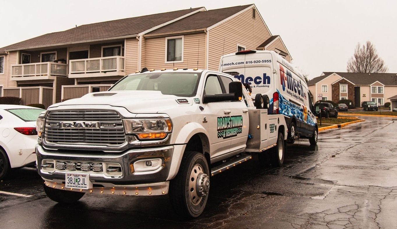 A tow truck is parked on the side of the road in front of a building.