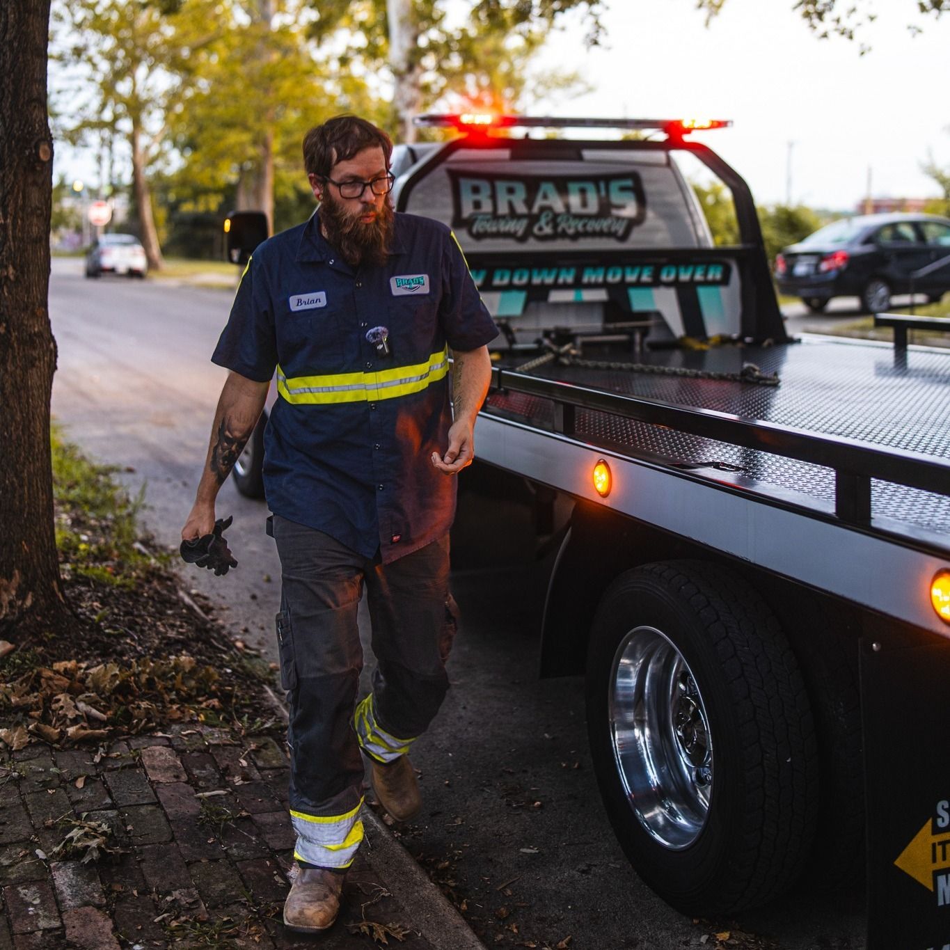 A man is walking towards a braud 's tow truck