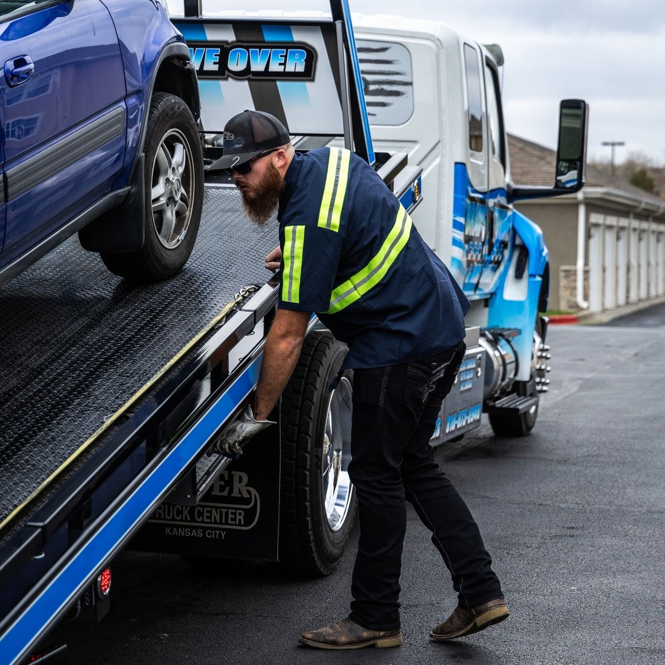 A man is loading a car onto a tow truck.