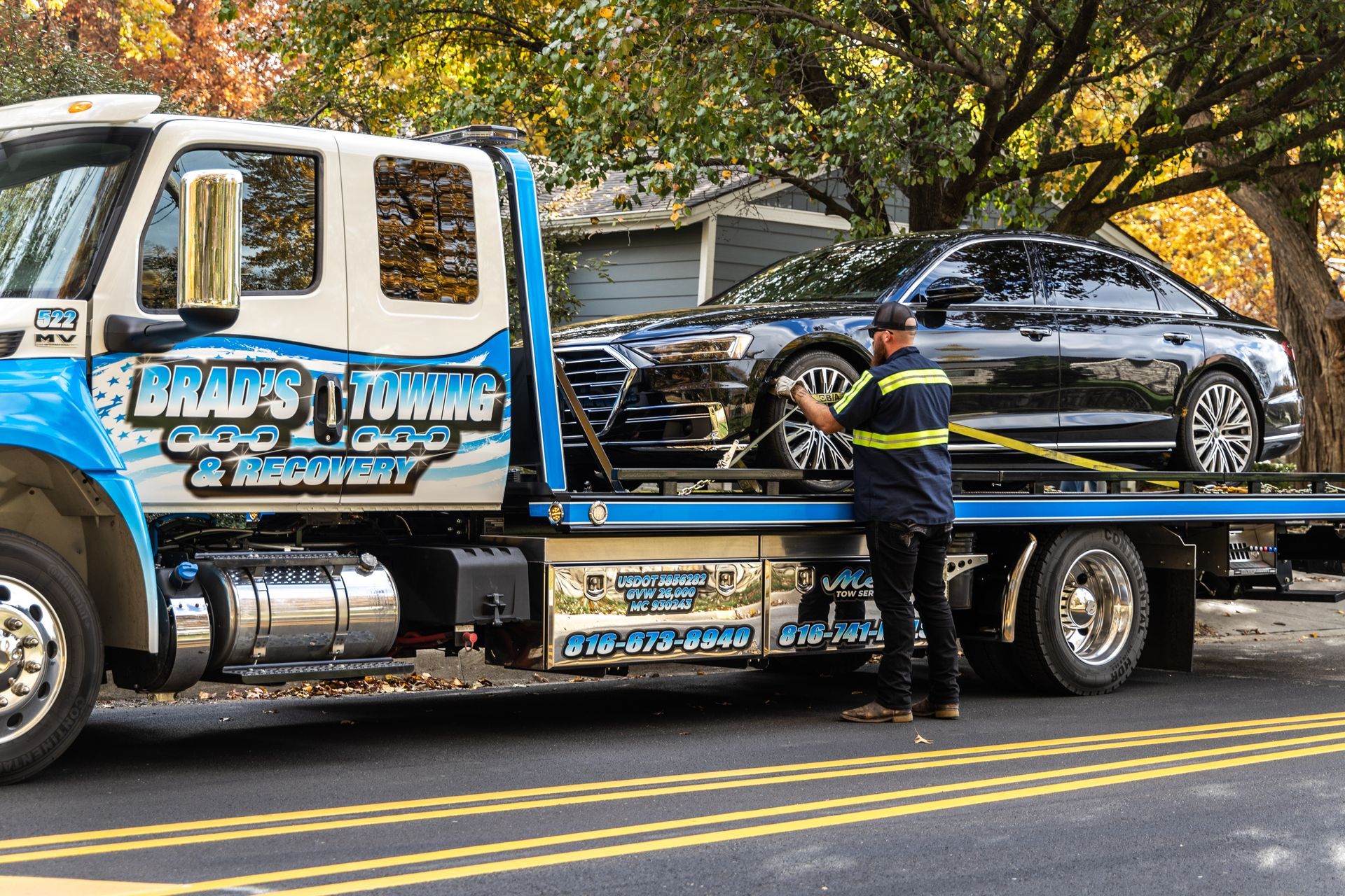 A tow truck is towing a car on a flatbed trailer.