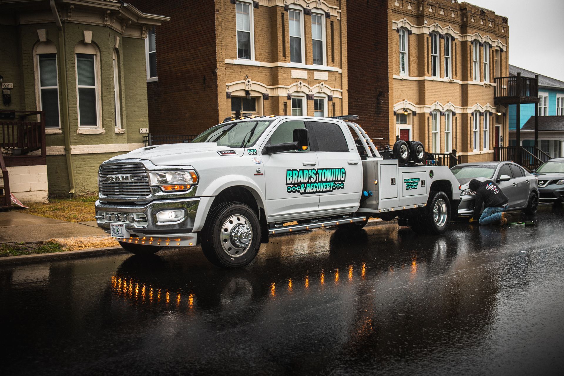 A white tow truck is parked on the side of the road in front of a building.