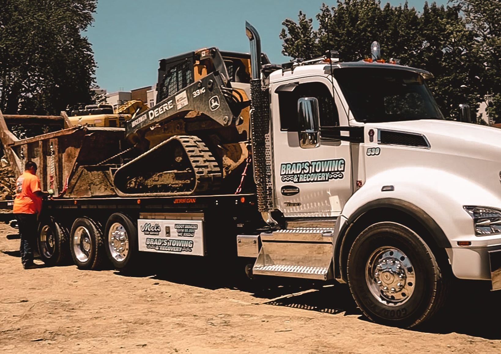 A white truck with a bulldozer on the back of it