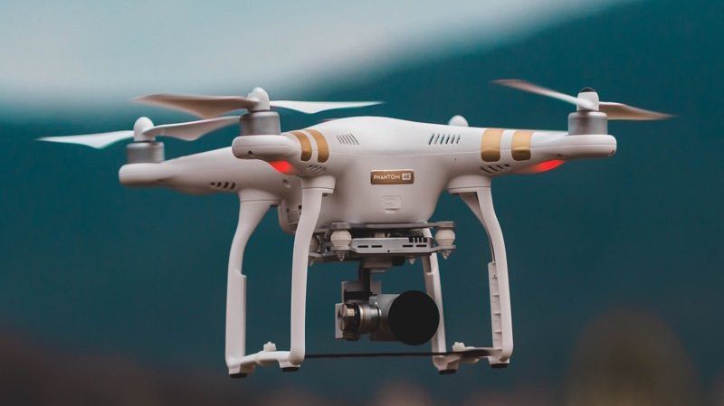 A drone is flying in the sky with a camera attached to it.
