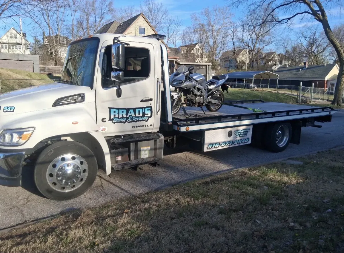 Flatbed tow truck providing emergency light duty passenger vehicle towing at the Kansas City International Airport parking garage.