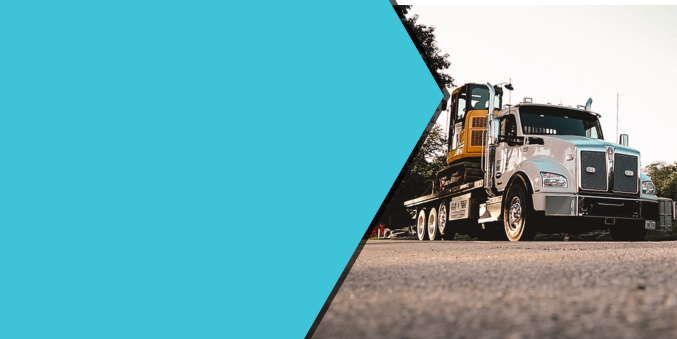 A semi truck with a yellow excavator on the back is parked on the side of the road.