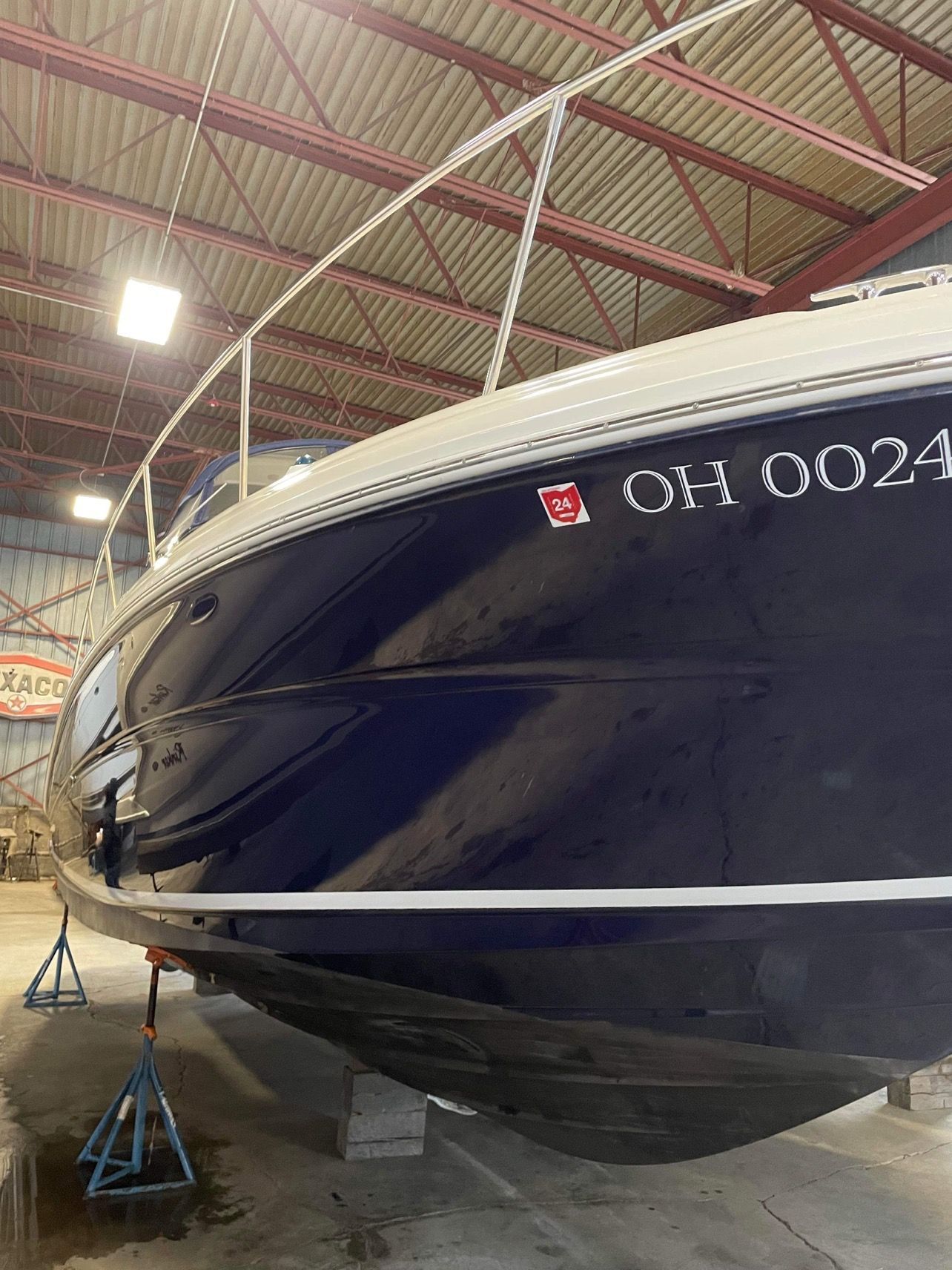 Large dark-blue boat on stands inside a warehouse, with white trim and the number 0014 on the bow