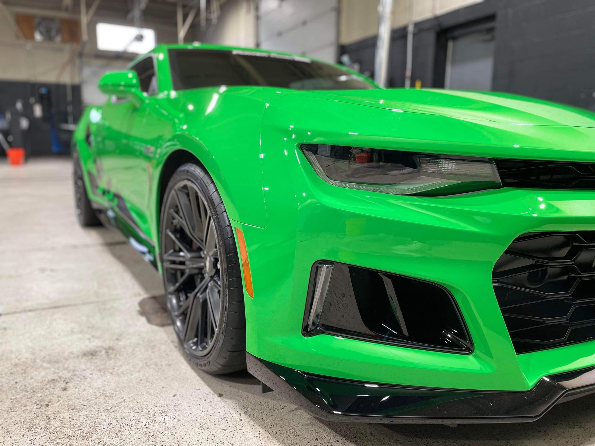 Bright green sports car in a garage, shown from the front-left side.