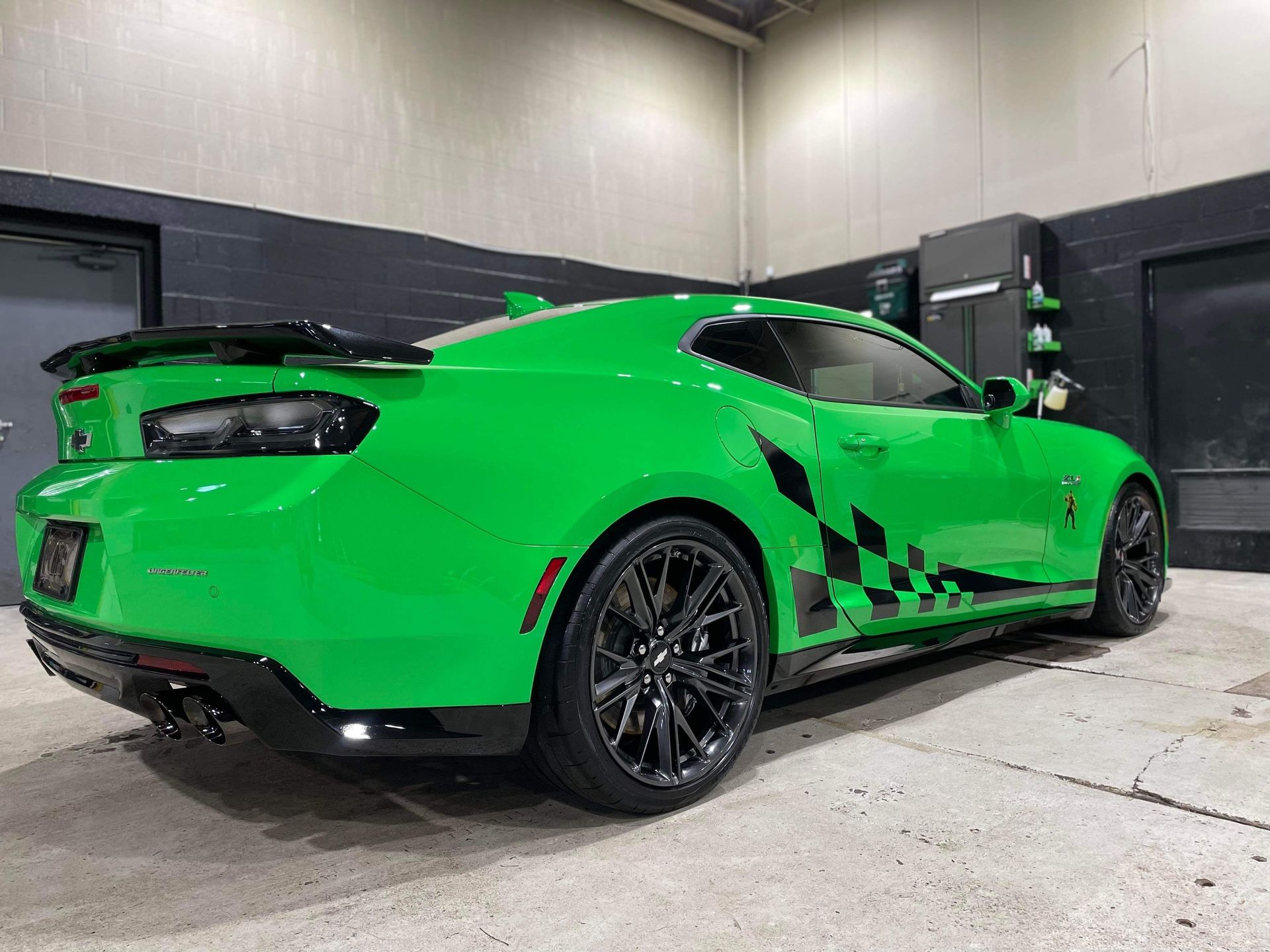 Bright green sports car with black rims parked indoors in a garage