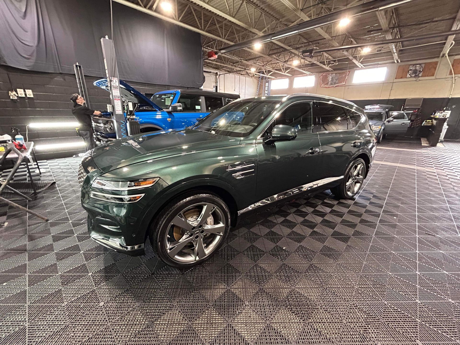 Dark green SUV on display in an indoor showroom with patterned floor lighting