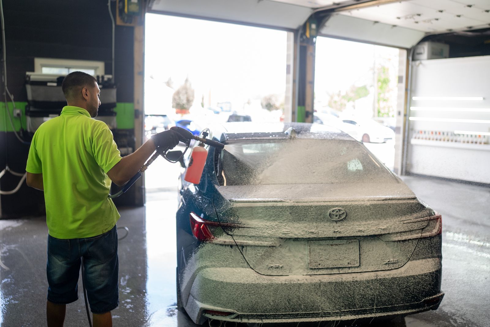 Two men washing a car in a soapy auto detailing shop