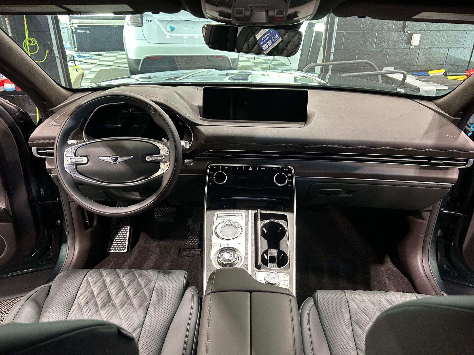 Luxury car interior with black leather seats, silver center console, and steering wheel view from the driver’s seat