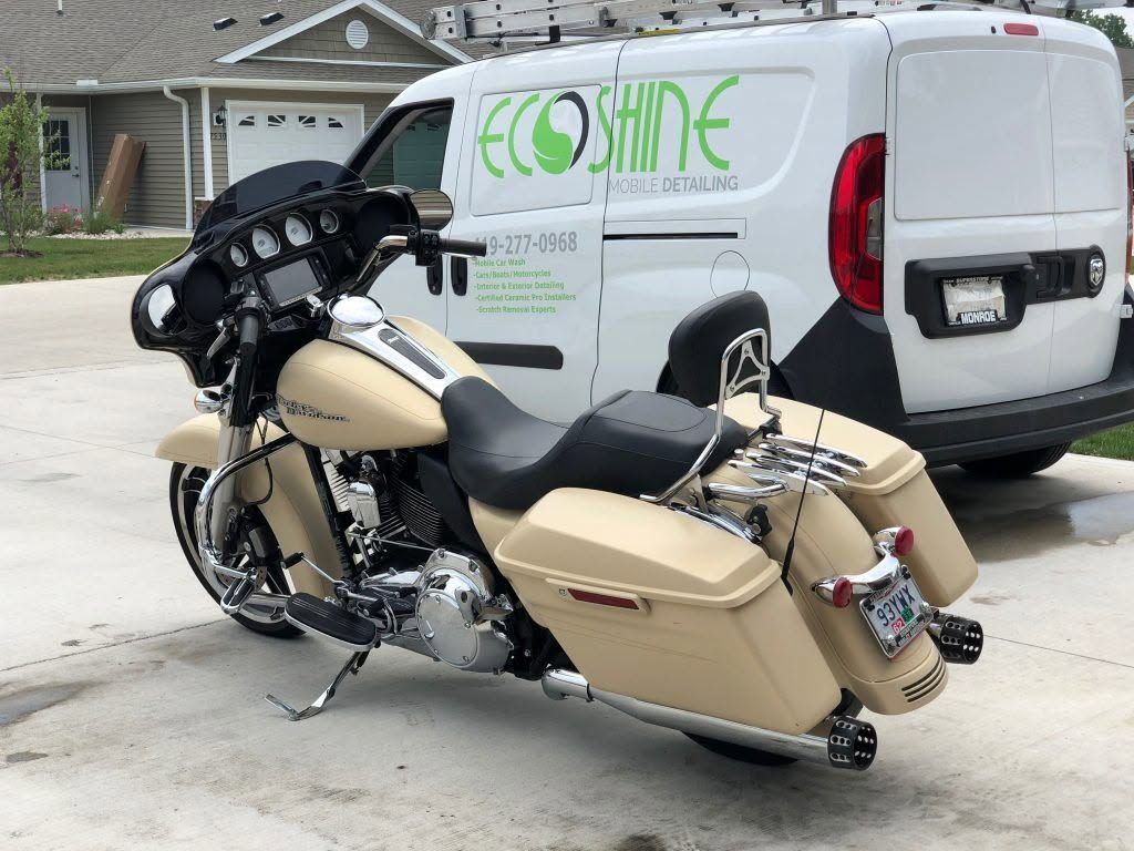 Tan touring motorcycle parked beside a white service van in a residential driveway