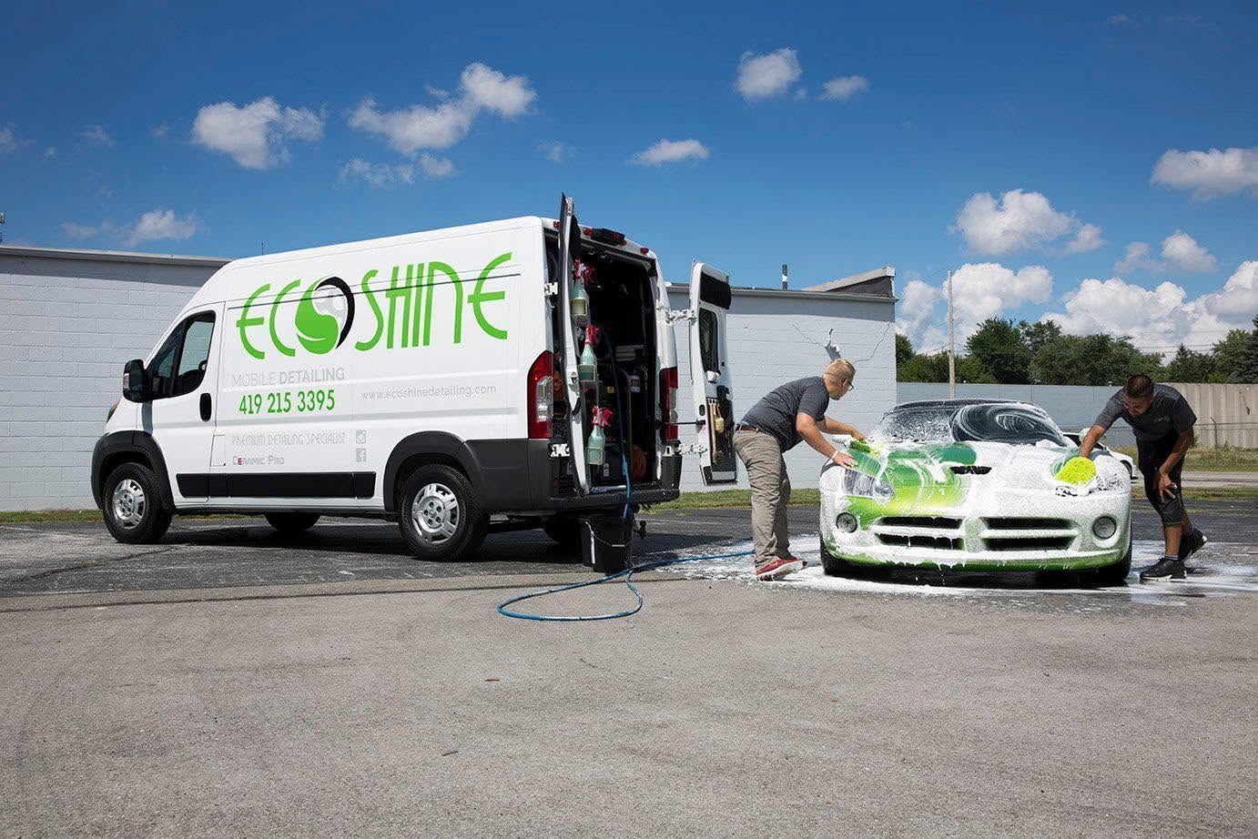 EcoShine van beside a white sports car being washed in a gravel lot under a blue sky