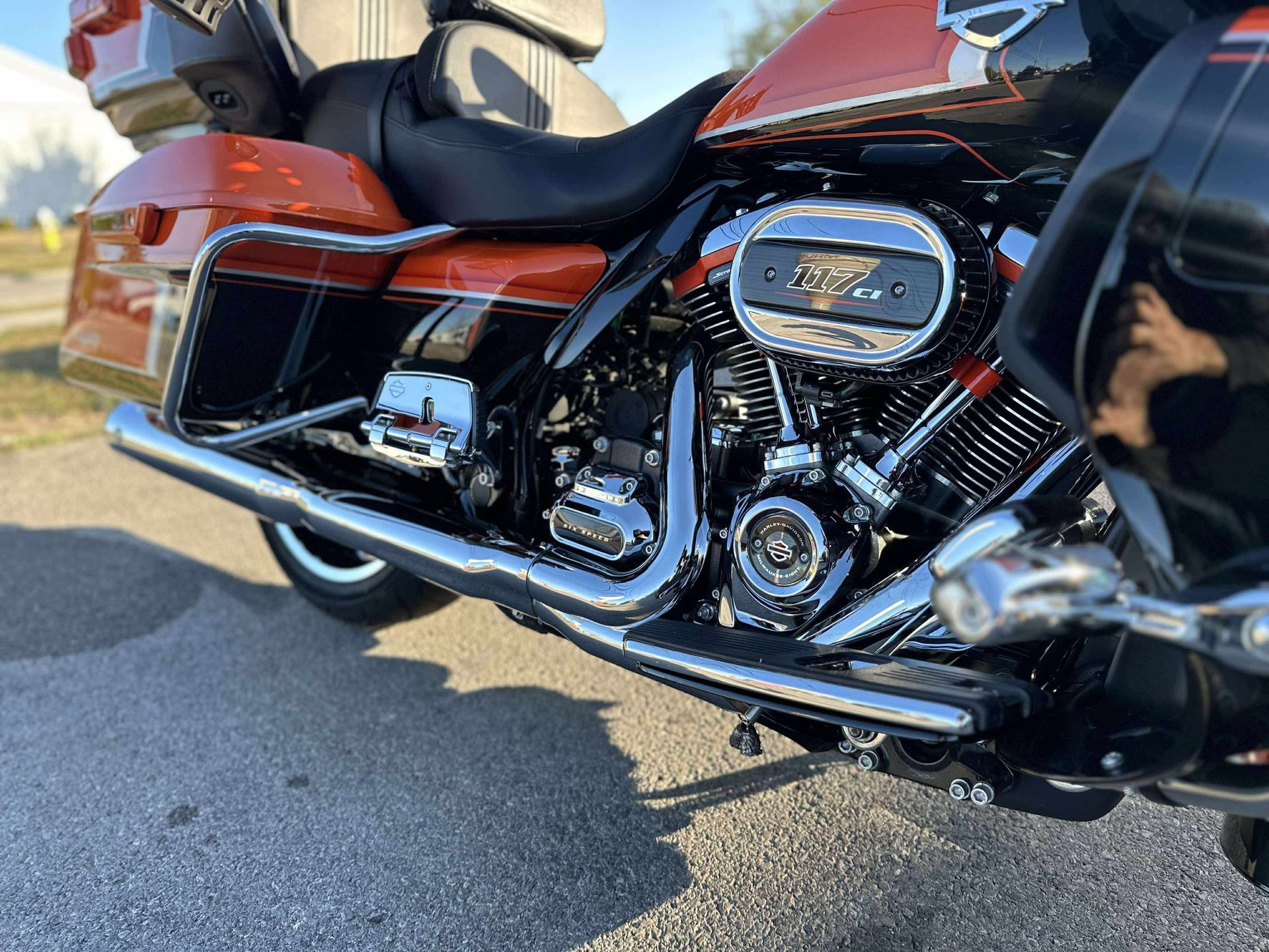 Close-up of a red-and-black motorcycle parked on asphalt, showing the chrome engine and exhaust.