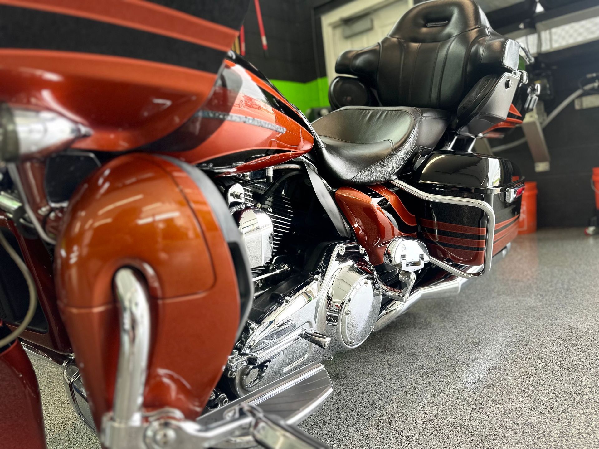 Orange and black motorcycle with chrome details parked indoors on a speckled floor