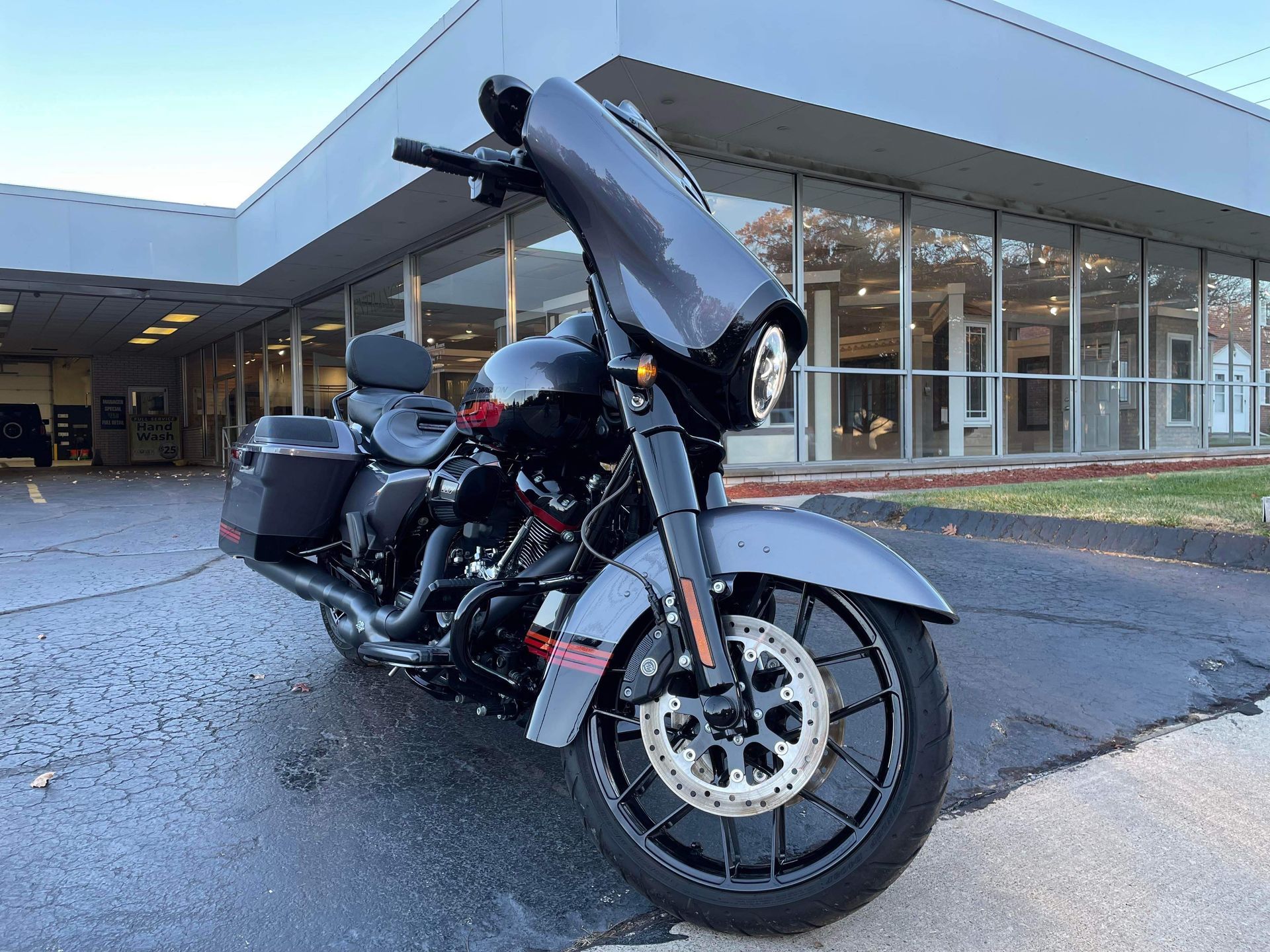 Black touring motorcycle parked outside a modern building on a wet pavement.