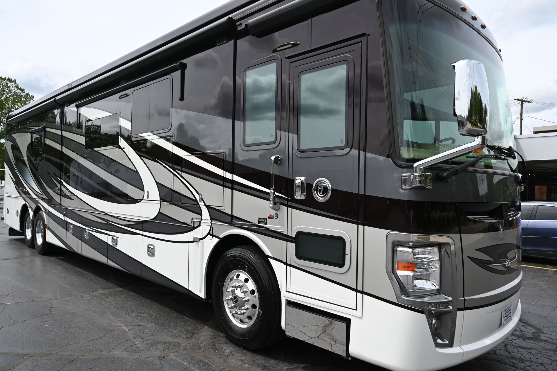 Black and white luxury RV parked outdoors, side view with reflective windows