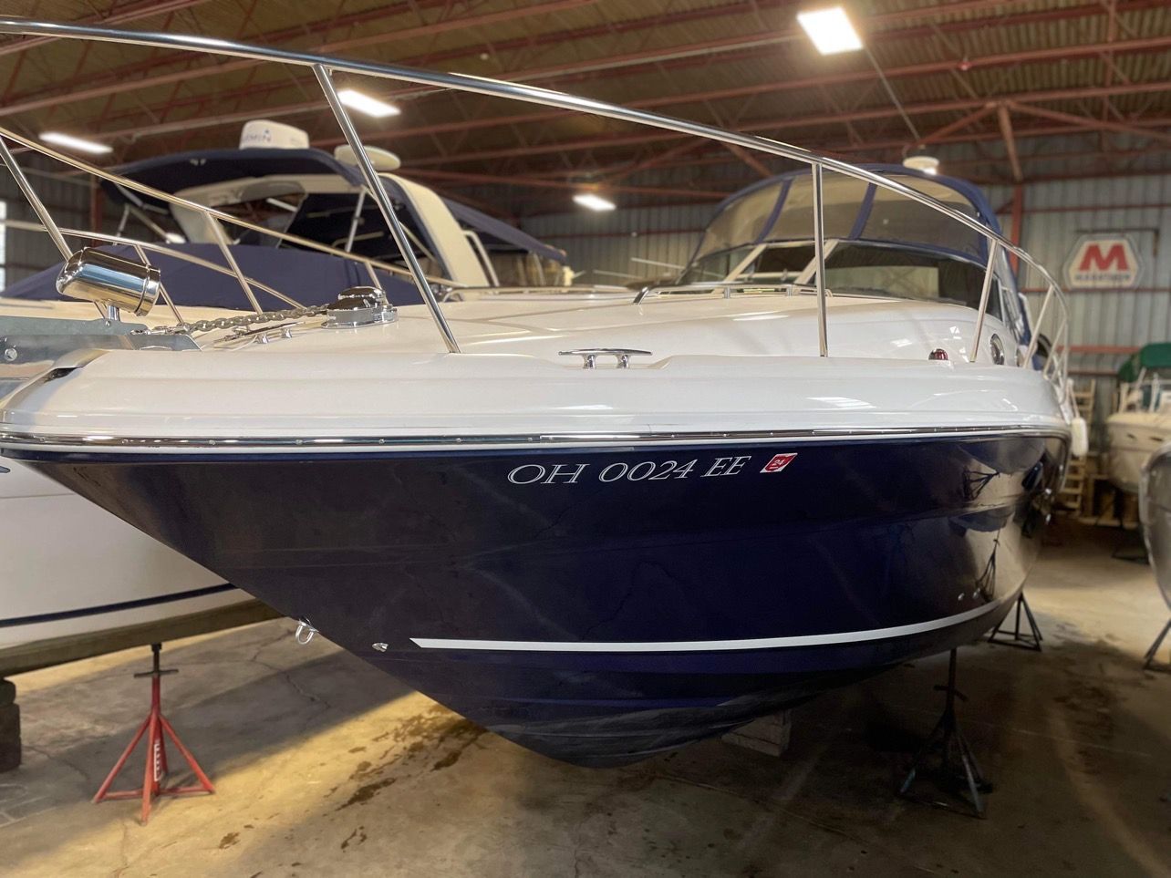 White and navy blue yacht on stands inside a boatyard warehouse