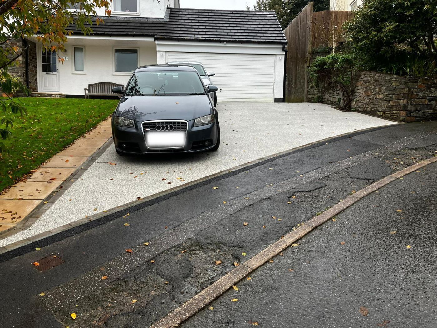 Grey resin driveway with 2 cars on it and a tarmac pavement in front of it.