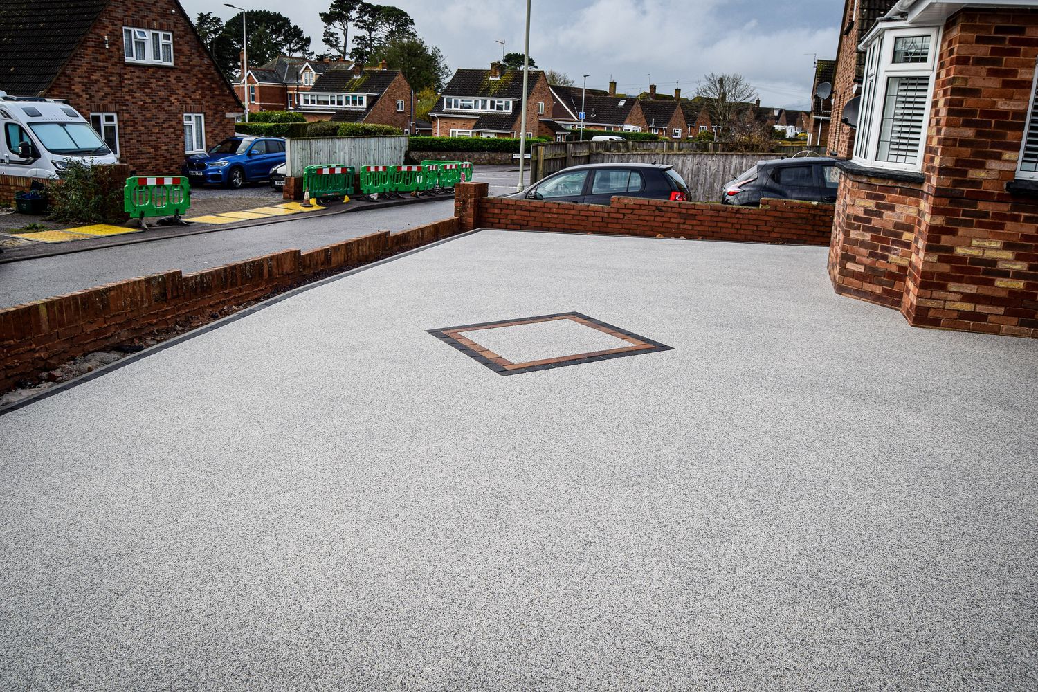 New driveway installation in grey with a wall around it.