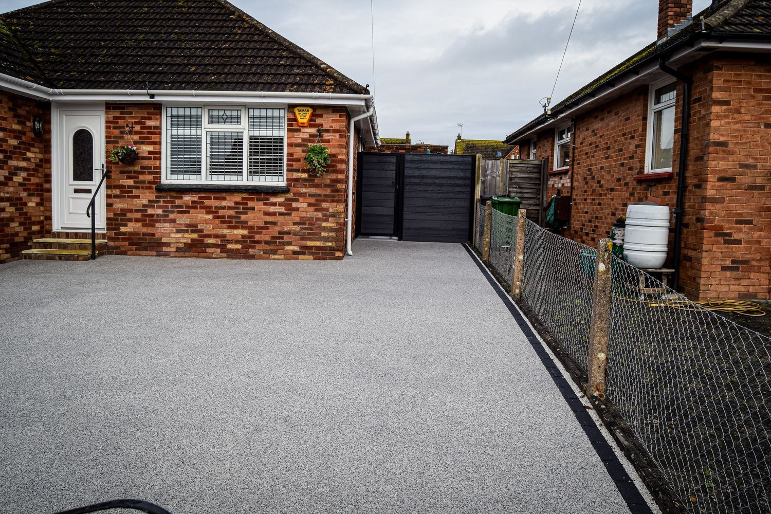 Plain grey driveway with black block paving edge.