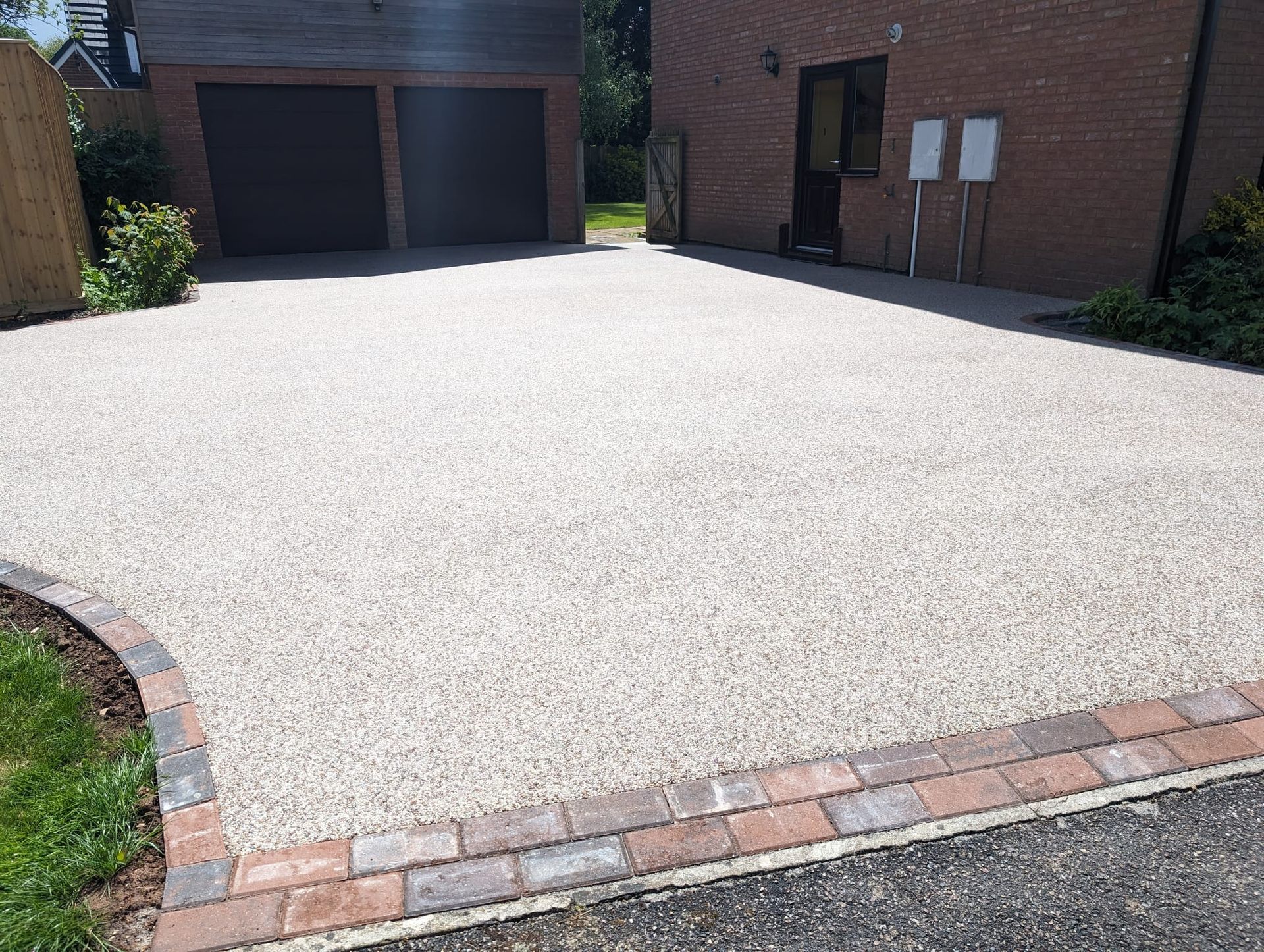 White resin driveway with a double red block border.