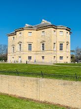 A large building with a fence around it is sitting on top of a lush green field.