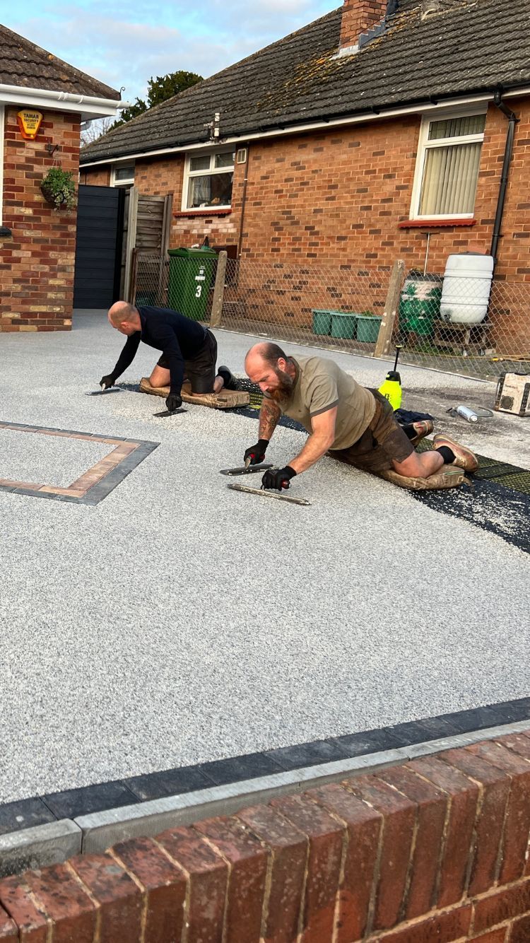Two men laying resin bound on a driveway.