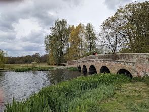 A bridge over a river in a park with trees in the background.