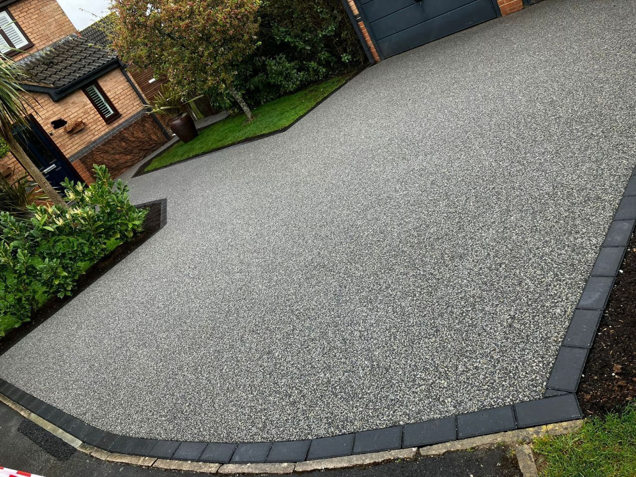 Grey resin driveway installation with new lawn in the background.