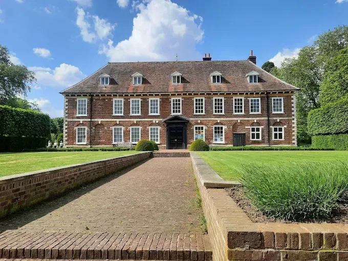 A large brick house with a brick walkway leading to it.