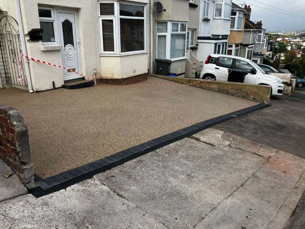 Resin driveway in a beige colour and black edge at the front made from block paviours.