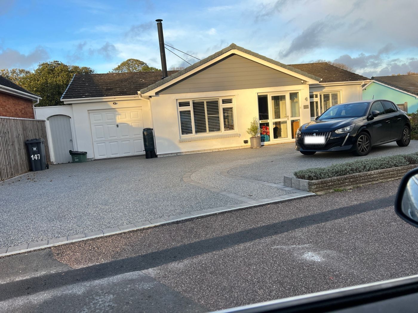 2-tone resin driveway in grey and white with a black car on it.