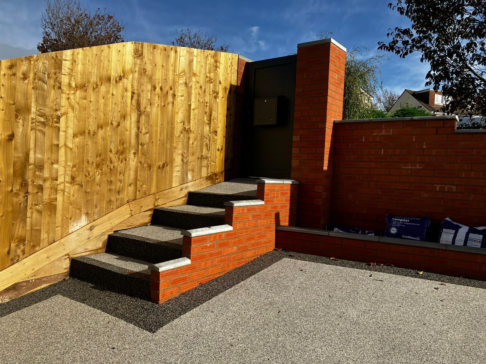 Grey and black 2-tone resin steps and driveway with a new brick wall.