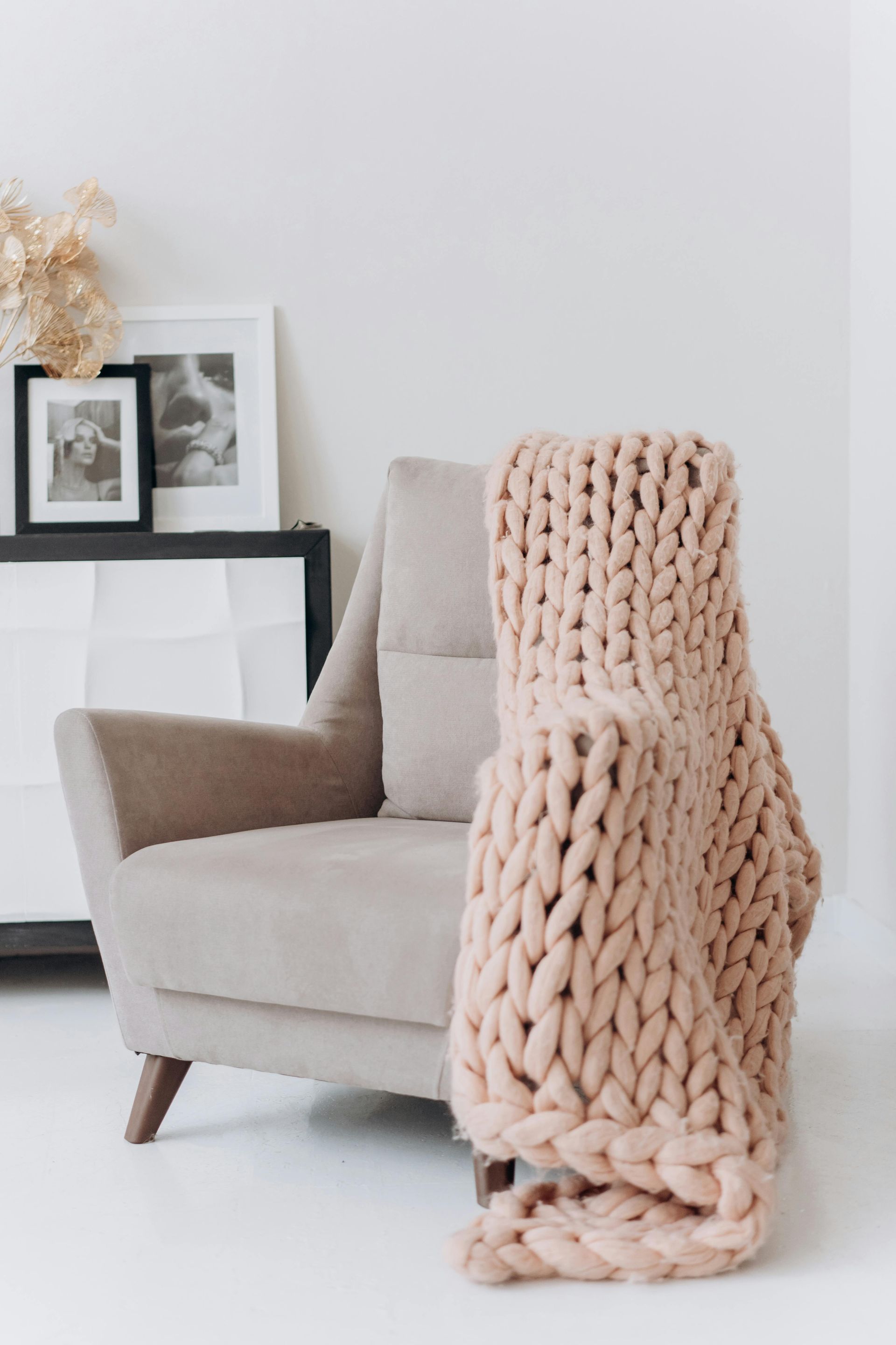 A hand holds a vacuum, cleaning the corner of a blue upholstered sofa. A hand holds a vacuum, cleaning the corner of a blue upholstered sofa.