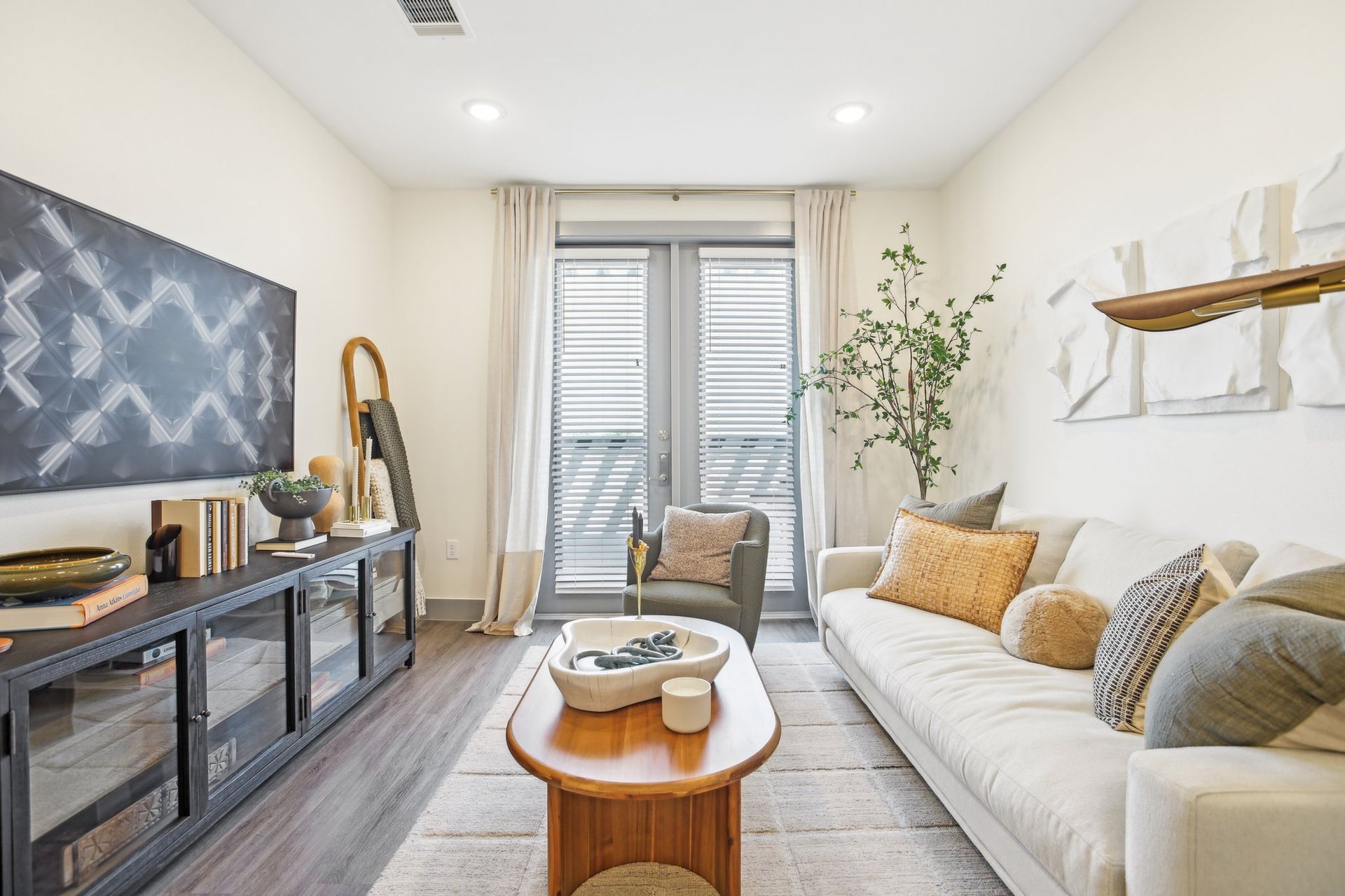 Living room with a cream sofa, wooden coffee table, and a large TV.