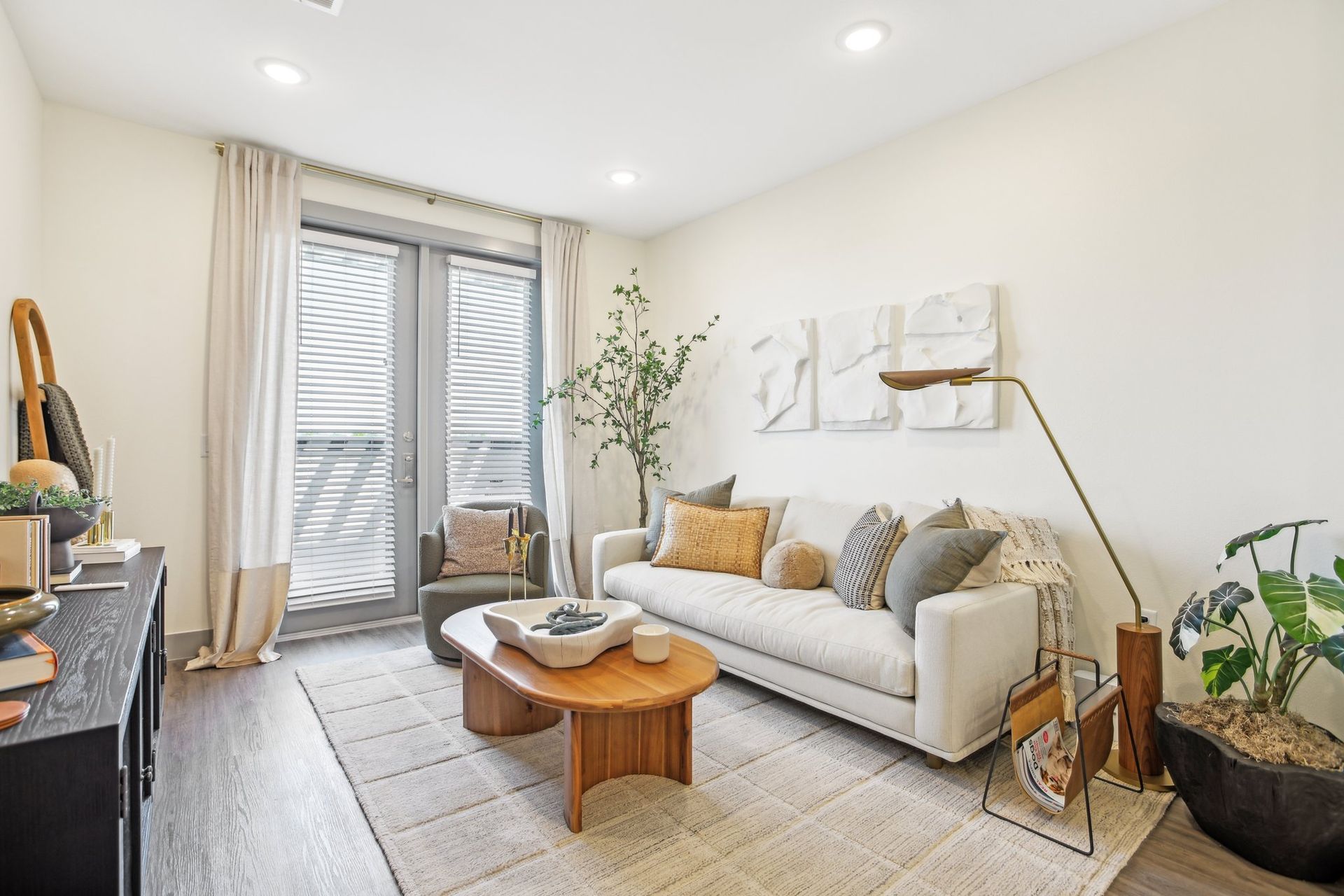 Living room with sofa, coffee table, and decor. Neutral tones with natural light.